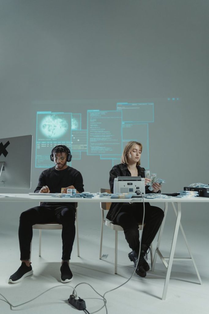 Two people sitting at a table using technology and gadgets in a modern setting.